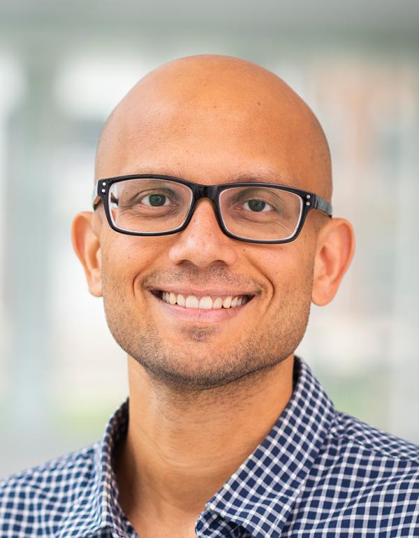 Dr. Pratyush Tiwary in glasses and blue-checked shirt.