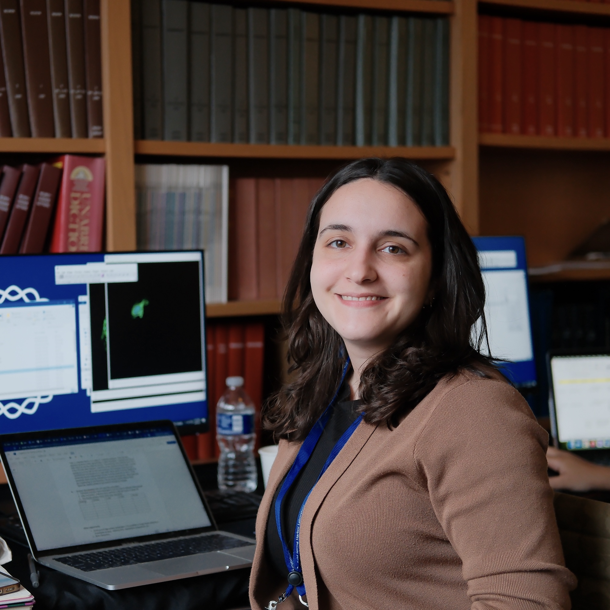 Laura Rodriguez sitting in front of a laptop and bookcases.