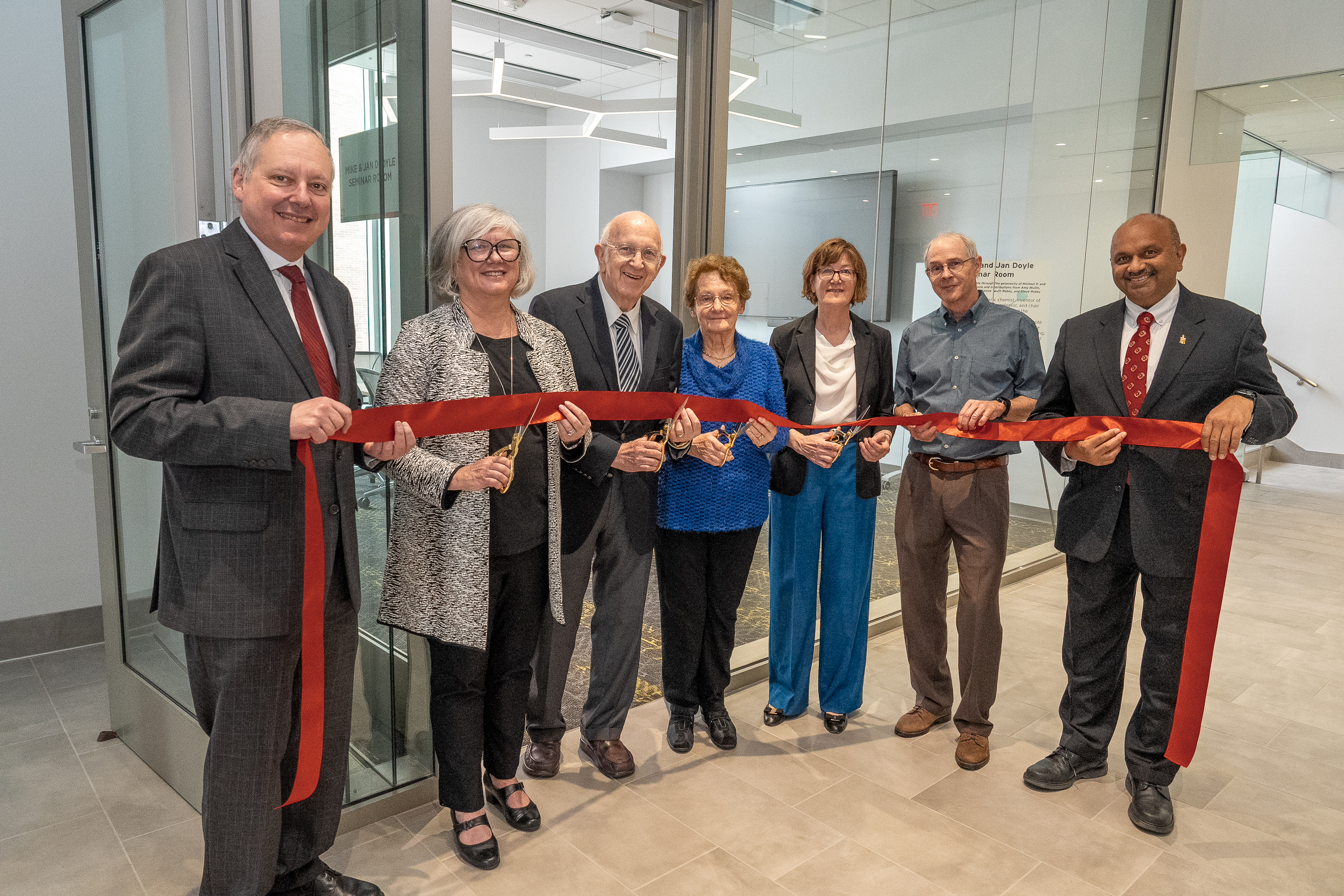 group cutting the ribbon for the Mike and Jan Doyle Seminar Room